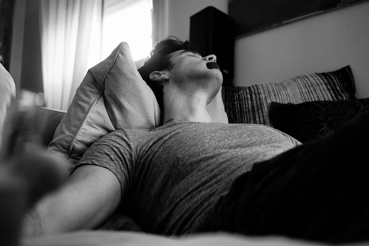Man sleeping on couch using mouth tape